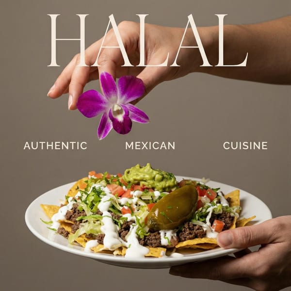 A hand holds a purple orchid above a plate of nachos with ground beef, guacamole, and a jalapeño.